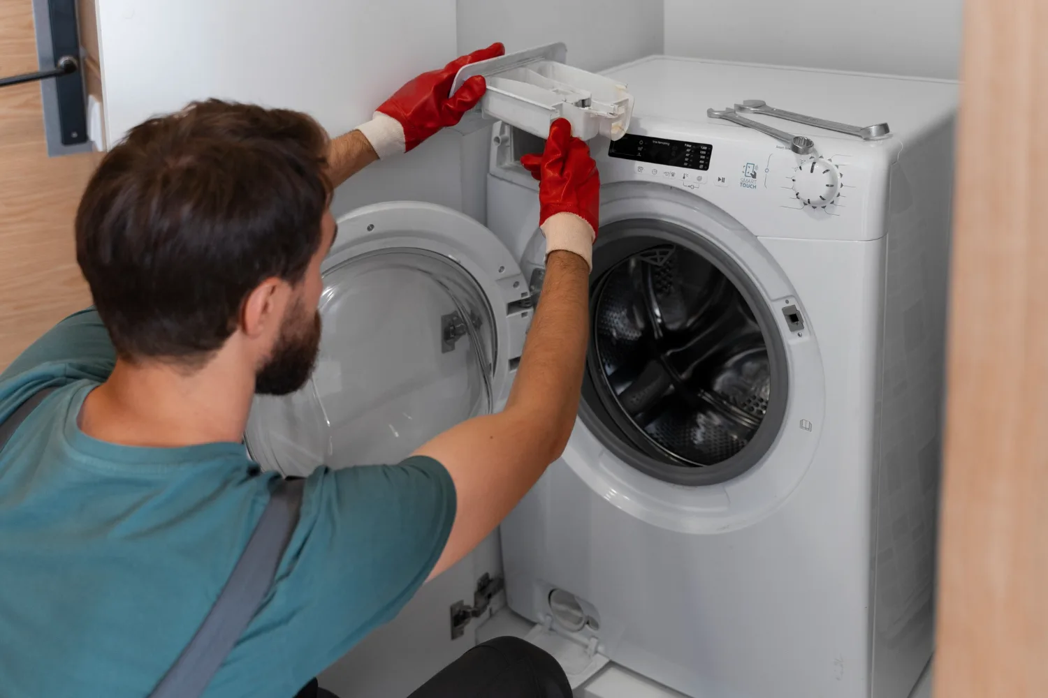 Técnico con guantes retirando el cajón del detergente de una lavadora de carga frontal