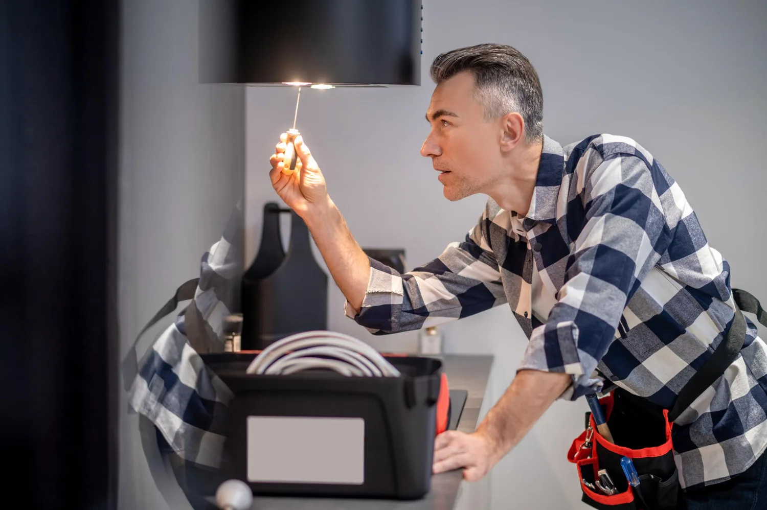 Técnico revisando con un destornillador la luz de una campana extractora